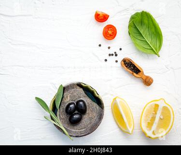 Food background with fresh herbs  tomato ,lemon slice , black pepper ,sage leaves ,sweet basil and olive oil over white wooden background  with flat l Stock Photo