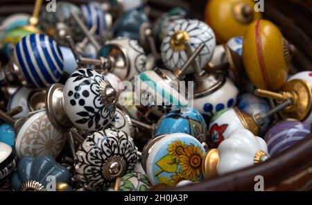 Old fashioned colorful ornate ceramic door knobs at flea market in Paris, France. Vintage furniture design background. Closeup. Selective focus. Stock Photo
