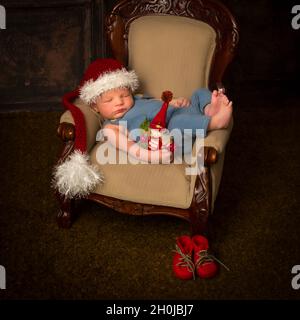 Sleeping newborn baby in Santa Christmas hat lying in a vintage armchair Stock Photo