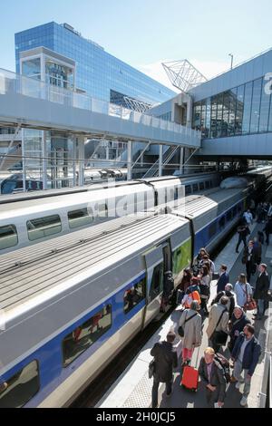 Rennes (Brittany, north western France): trains alongside the platforms in the railway station People getting on a first class train with office build Stock Photo