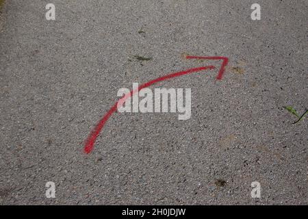 Red curved arrow painted on concrete road with spray paint Stock Photo