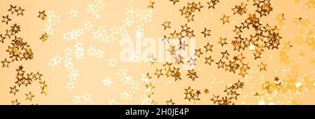 Banner with shiny stars confetti scattered on a gold background. Stock Photo