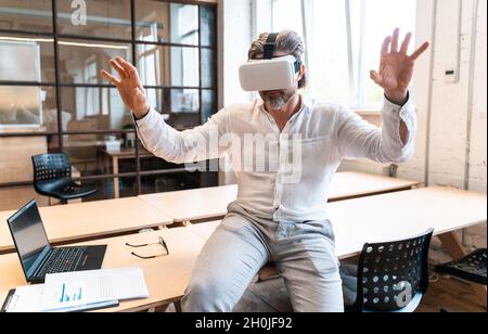 senior business man sitting in his office and using mixed reality to develop a new project Stock Photo