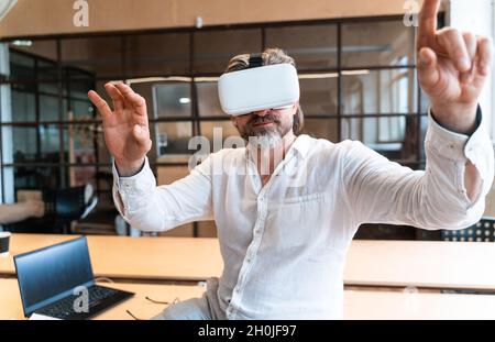 senior business man sitting in his office and using mixed reality to develop a new project Stock Photo