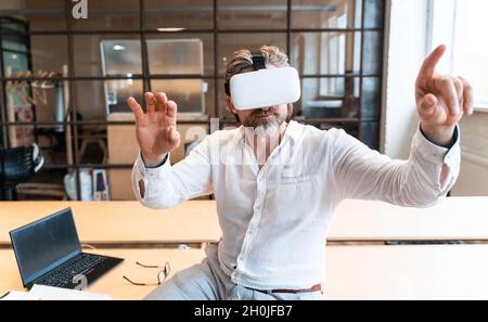 senior business man sitting in his office and using mixed reality to develop a new project Stock Photo