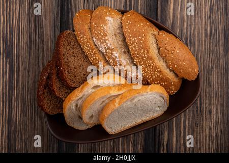 top view of breads as sliced seeded brown cob rye and white ones in bowl on wooden background Stock Photo