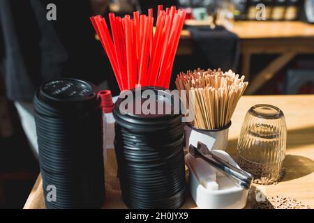In a coffee shop on the table, covers on coffee cups, sticks, sugar and plastic tubes Stock Photo