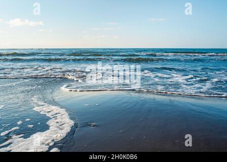 Beautiful wild beach of the Sea of Okhotsk, Sakhalin island, Nevelsk, Russia. Endless sea and clear blue sky. Waves are washed up to the shore. Stock Photo