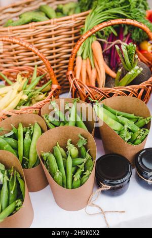 Vegetables packed in kraft paper on the counter - top-quality farm natural products - peas, carrots, beans, cucumbers, beets, jam Stock Photo