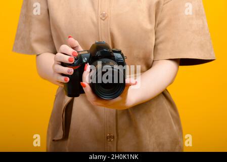 Image of hands with digital photo camera on yellow background Stock Photo