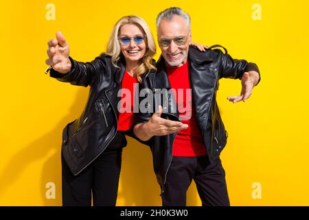 Portrait of beautiful handsome pensioner grey-haired friends spouses fooling dancing isolated over shine yellow color background Stock Photo