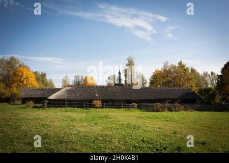 An old rustic wooden hut. In the background there is a rustic wooden church. Stock Photo