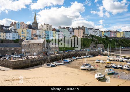 Tenby Harbour, Pembrokeshire, Wales, the United Kingdom. Boats on the beach at low tide. Colorful buildings of popular Welsh resort on a sunny Summer day. Tenby, UK - September 20, 2021 Stock Photo