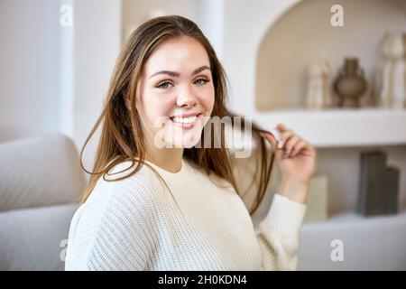 Portrait of cheerful caucasian woman on sofa indoors. Stock Photo