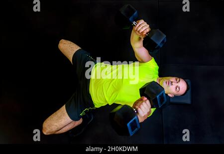 young adult man fitness training indoor in gym isolated on black backgound doing weight lifting. directly above view of person making exercises. fit Stock Photo