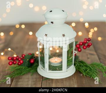 White lantern with ornaments and Christmas lights on rustic wooden table. Copy space. Stock Photo
