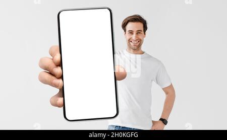 Mockup Image Of Young Handsome Man Holding Smartphone With Big Blank Screen Stock Photo