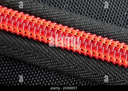 extreme close up close up of a part of a red plastic zipper sewn into a black pencil case Stock Photo