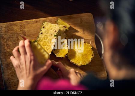 Woman peels a pineapple with a knife. Tropical fruits Stock Photo
