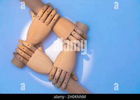 close up of hands holding each other. Two pairs of wooden prosthetic hands are staggered to build a cooperative appearance. A combination of wooden ha Stock Photo