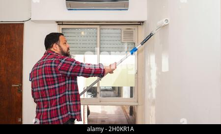 middle age man painting a wall of his apartment Stock Photo