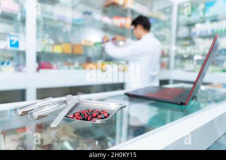 Select the focus on the drug, A male pharmacist working in chemist shop or pharmacy. Pharmacist using the laptop at the pharmacy. Stock Photo