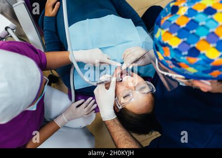 Professional dentists performing a procedure on a patient in the dentist office. Stock Photo