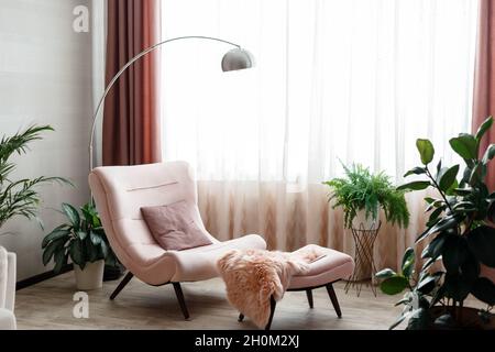 Stylish room interior with Cozy empty armchair near window gray wall with nobody. Cozy place to relax home interior on couch among flowers domestic Stock Photo