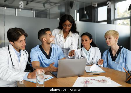 Puzzled doctors discussing medical cases, using laptop Stock Photo