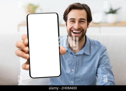 Excited Young Man Demonstrating Smartphone With Big Blank White Screen At Camera Stock Photo