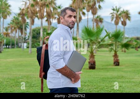 Portrait of serious confident mature man with laptop outdoors Stock Photo
