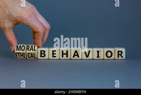 Moral or ethical behavior symbol. Businessman turns cubes, changes words ethical behavior to moral behavior. Beautiful grey background, copy space. Ps Stock Photo