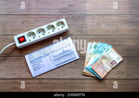 Electric power strip with power switch, electricity bill and pile of euro bills Stock Photo