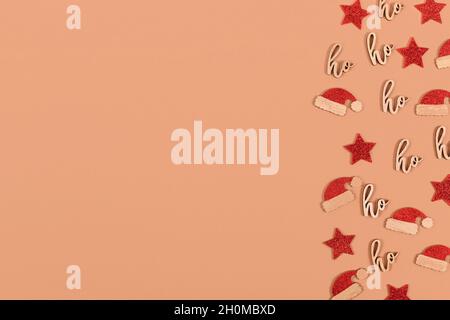 Christmas decorations in shape of stars, santa hats and text ornaments saying 'ho ho ho' on side of beige background with copy s Stock Photo