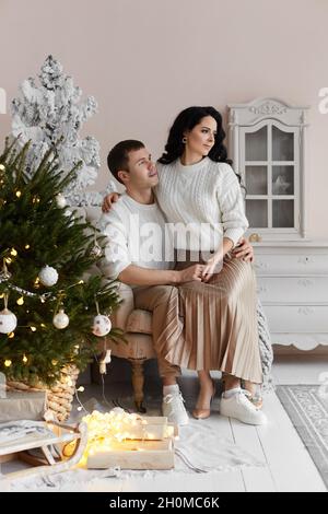 Handsome man and young pretty woman spend time at home on Christmas eve Stock Photo