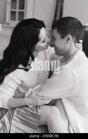 Lovely couple in white cozy sweaters posing at home during Christmas time Stock Photo