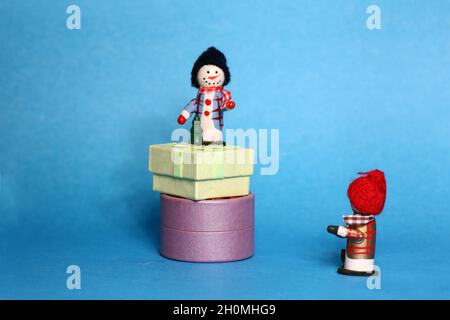 christmas concept - two snowman with gift boxes isolated on blue background Stock Photo