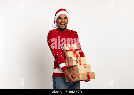 Happy black guy in santa hat holding christmas gifts Stock Photo