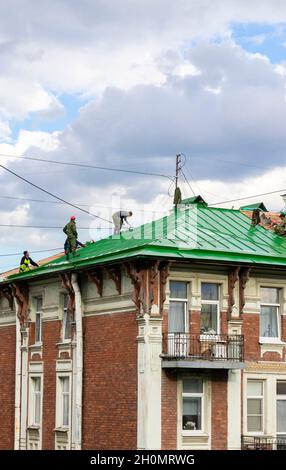 Workers on rooftop changing roof covering sheeting on a historical modernist building. Maintenance and remodeling work in St Petersburg Russia Stock Photo