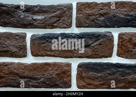Close-up texture of a dark red scratched brick wall with a white seam Stock Photo