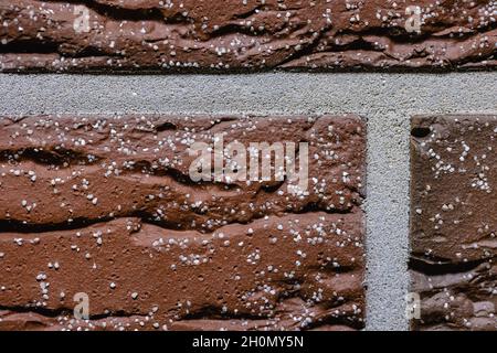 Close-up texture of a red scratched brick wall with a gray seam Stock Photo