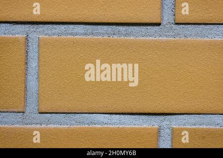 Close-up texture of a yellow brick wall with a gray seam Stock Photo