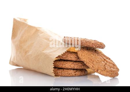 Several fragrant dark brown, oatmeal cookies in a paper bag, close-up, isolated on white. Stock Photo