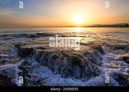 Unbelievable sunrise is reflecting on the water. Morning landscape with mountains. Beautiful sea with waves. Romantic relax place. Agia Marina Beach, Stock Photo