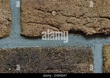 Close-up texture of a brown scratched brick wall with a gray seam Stock Photo