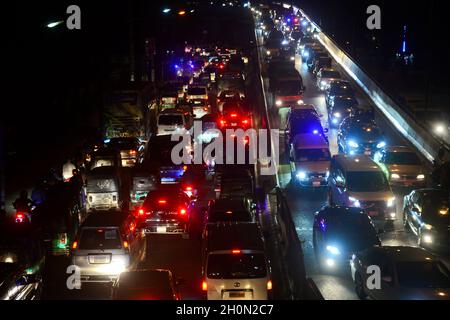 Commuters make their way through a traffic jam at night during Covid-19 Coronavirus pandemic in Dhaka, Bangladesh, on October 13, 2021.Last 10 years in Dhaka, average traffic speed has dropped from 21 km/hour to 7 km/hour, only slightly above the average walking speed. Congestion in Dhaka eats up 3.2 million working hours per day according to static reports. Stock Photo