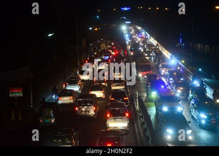 Commuters make their way through a traffic jam at night during Covid-19 Coronavirus pandemic in Dhaka, Bangladesh, on October 13, 2021.Last 10 years in Dhaka, average traffic speed has dropped from 21 km/hour to 7 km/hour, only slightly above the average walking speed. Congestion in Dhaka eats up 3.2 million working hours per day according to static reports. Stock Photo