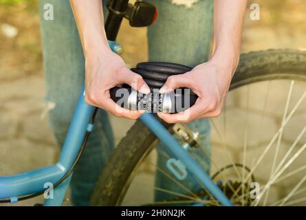 Close up of female hands holding combination bike lock in front of bicycle Stock Photo