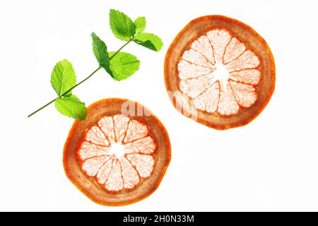 Two thin transparent slices of grapefruit and mint leaves in clearance - isolated on white Stock Photo