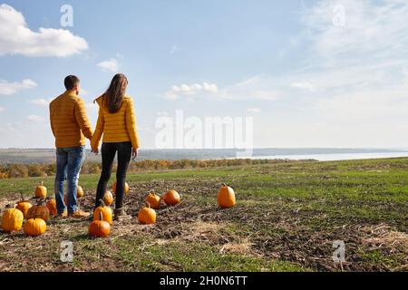 Young couple enjoying sunset in pumpkin patch field Stock Photo